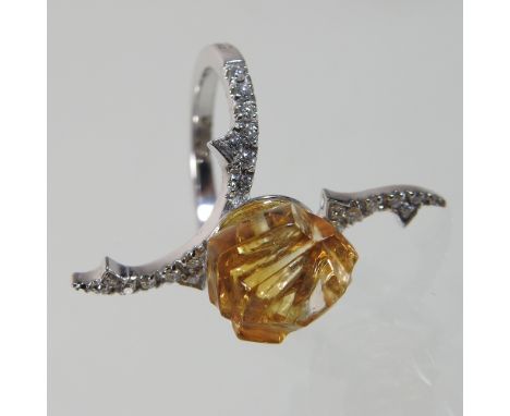 An 18 carat gold carved yellow topaz and diamond ring, of rose and thorn design, the crossover setting set with a continual r