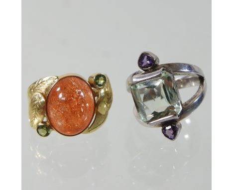 A modern unmarked sunstone cabochon and peridot ring, size M, together with a white metal gem set ring, size J/K (2)