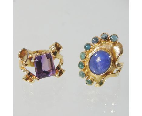 An unmarked cabochon dress ring, of oval asymmetrical shape, 3cm high, size O, together with a baguette cut single stone ring