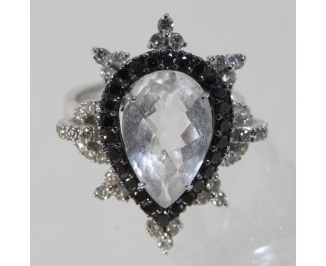 An 18 carat gold clear quartz, diamond and black diamond cluster ring, the central facet cut tear shaped stone, within a star