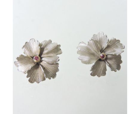 A pair of 14 carat two colour textured gold and ruby earrings, each in the form of a flower head with five petals, with a hin
