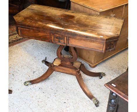 A Regency ebony inlaid satinwood card table, the revolving fold-over top with canted corners, raised on a lyre form support t