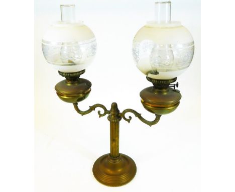 An early 20thC brass two branch lamp, with cylindrical stem, frosted and clear glass shades and clear glass funnels, on a ste