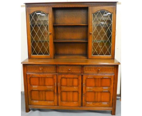 A 20thC Ercol dark wood display cabinet, with moulded frieze raised above open shelves flanked by glazed cabinets above friez