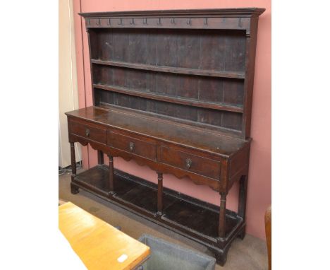 An 18th century oak dresser with plate rack back, the plate rack with eleven iron hooks above two fixed shelves, the base wit