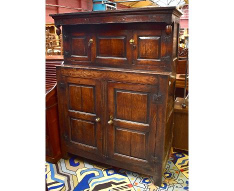 A late 17th century oak court cupboard, the upper section with twin cupboard doors above a base of twin panelled cupboard doo