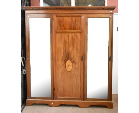 An Edwardian mahogany and boxwood strung triple wardrobe with moulded dentil cornice above two full length bevelled mirror do