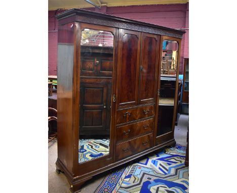 An early 20th century mahogany wardrobe with twin central panelled doors enclosing rail and fitted interior of three base dra