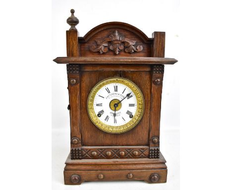 An early 20th century carved oak mantel clock, the circular enamelled dial set with Roman numerals and marked Fattorini &amp;