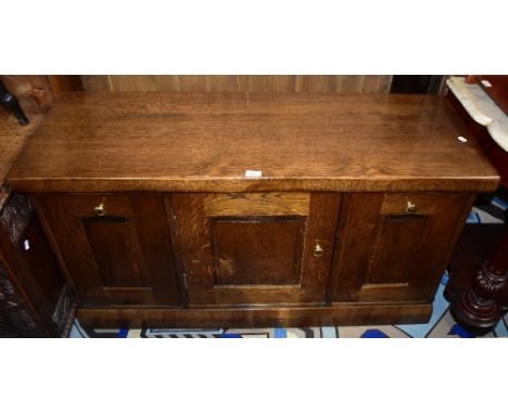 A reproduction oak miniature sideboard, the central door enclosing two shelves with storage compartments to either side, 67.5