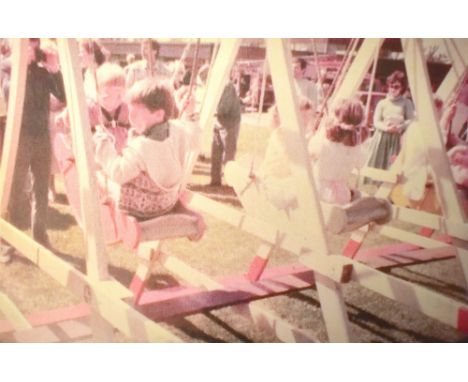 A vintage painted wooden fairground swing boat ride with six painted boats.