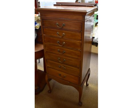 An Edwardian mahogany music cabinet with raised back above seven graduated drawers with fold down fronts, raised on cabriole 