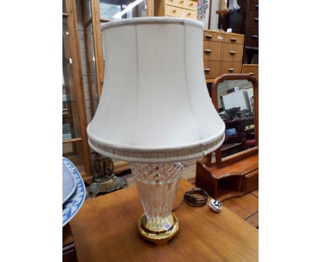 A cut glass and brass table lamp with cream shade   There is a chip to the bottom of the cut glass but is otherwise in good c