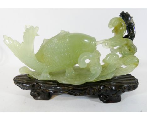 An oriental jade carving of a carp on hardwood base 20cms long   some losses to the top fin 