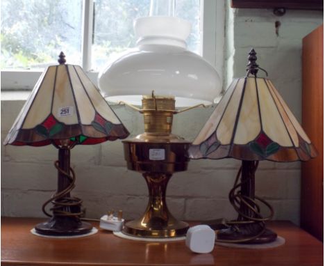 A pair of Tiffany style decorated table lamps with shades and a brass oil lamp