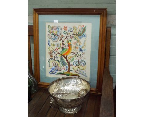 A plated fruit bowl with lion mask handles, a serving ladle and a needlework picture of a parrot 