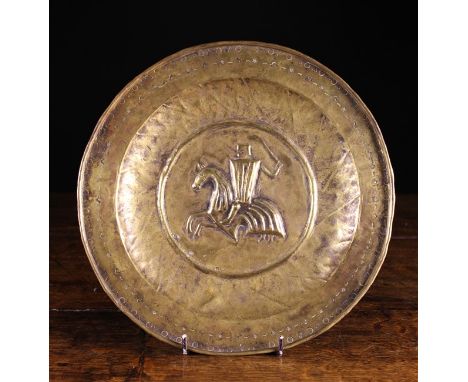 A Brass Alms Dish, N. Italy Circa 1500. The repoussé centre panel depicting a knight on horseback wielding a sword within a p