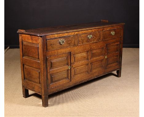 An 18th Century Joined Oak Enclosed Dresser. The two plank top with moulded edge above three frieze drawers framed by cock be