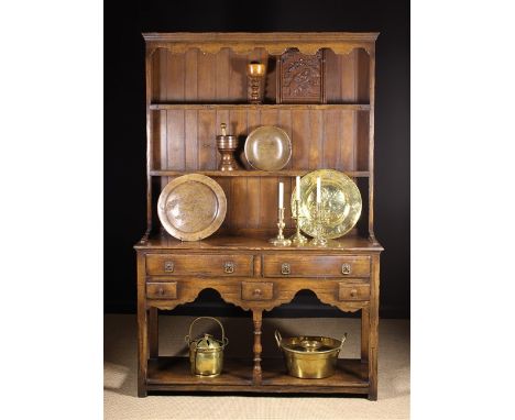 A Small 18th Century Style Oak Dresser with Rack. The plank-backed rack having a scalloped frieze rail above two shelves with