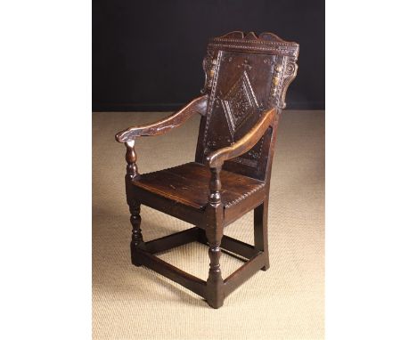 A 17th Century English Oak Wainscot Chair. The shaped top rail with decorative chip carved channels above a lozenge carved ba