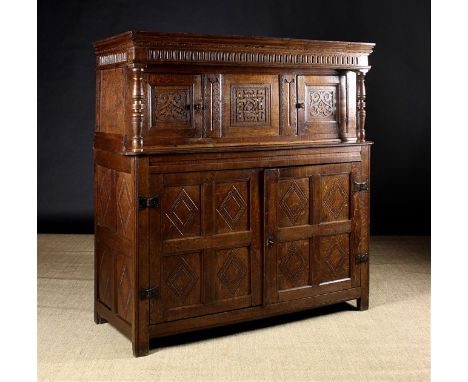 An 18th Century Oak Court Cupboard. The upper section with nulled frieze above two panel doors carved with arabesque strapwor