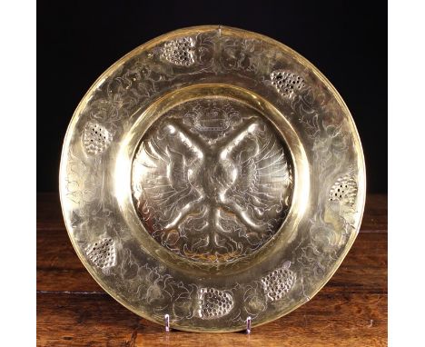 A 16th Century Repoussé Brass Alms Dish. The centre panel depicting the crest of Charles V, Dinant, framed in a border of fru