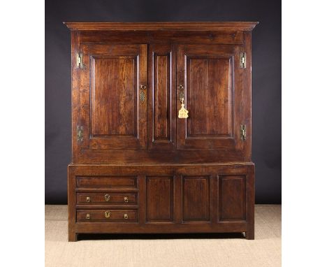 An 18th Century Oak Press Cupboard having two panelled doors opening to reveal hanging space extending into a panel-fronted b
