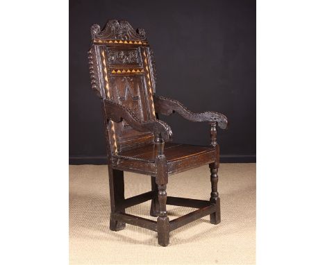 A 17th Century Yorkshire Inlaid Oak Wainscot Chair. The shaped cresting rail carved with voluted S-scrolls incorporating pend