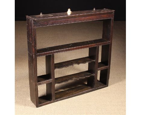 A Late 18th Century Hanging Wall Rack having an open shelf to the top above small side shelves flanking two serpentine edged 