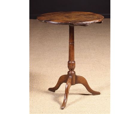 A Small 18th Century Oak Tilt Top Tripod Wine Table. The planked round top on a turned centre column and silhouette cut outsw