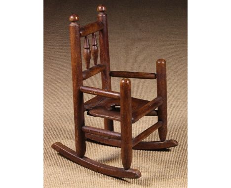 A 19th Century Child's Rocking Commode Armchair. The back with two baluster spindles between turned uprights standing on a tu