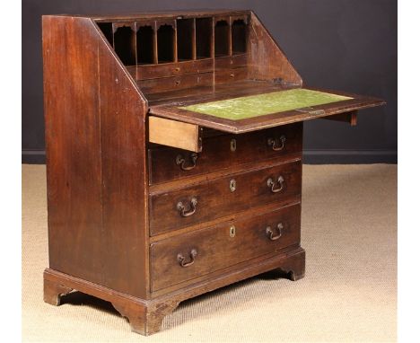 A Late Georgian Oak Bureau. The sloped fall front on loper supports opening to reveal a bank of pigeon holes and drawers with