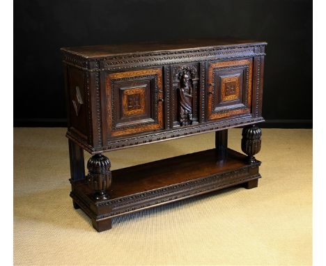 A 17th Century & Later Carved & Inlaid Oak Livery Cupboard. The two cupboard doors inlaid with bands of intricate chequerwork