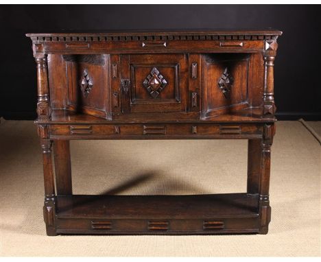 A 17th Century Cheshire Oak Canted Livery Cupboard, Circa 1630.  The dentil moulded top above a canted cupboard with decorati