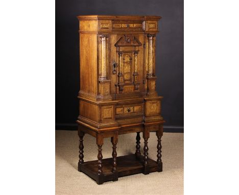 A Small Continental Oak Cupboard on Stand inlaid with decorative bands and adorned with figured elm columns and veneers. The 