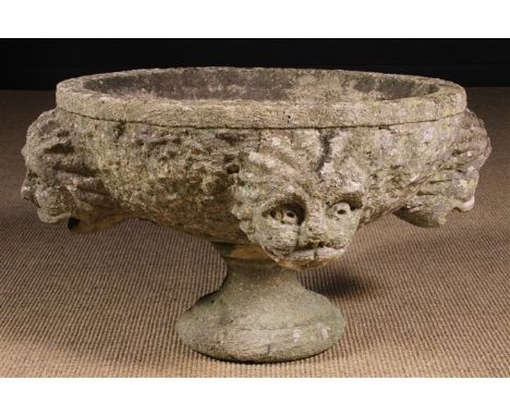 An Early Carved Limestone Fountain. The sides of the round basin carved in relief with four protuberant grotesque heads; thei