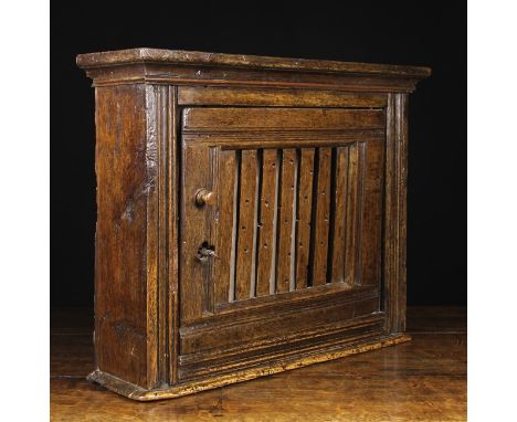 A Small Late 17th/Early 18th Century Joined Oak Mural/Food Cupboard. The door having a slatted panel pierced with ventilation