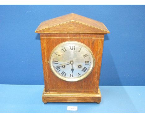 An Oak cased mantle clock with inlay string standing on ball feet, having Roman numerals, with key and pendulum,13" tall x 9"