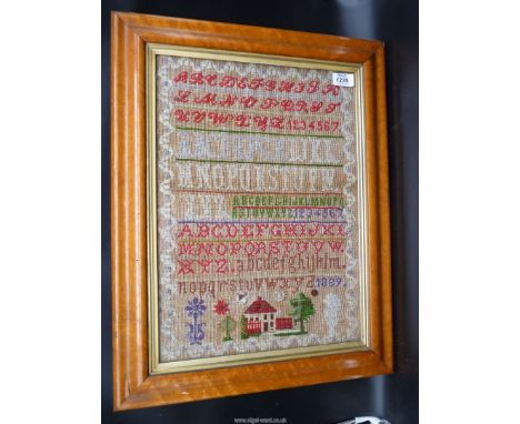 A Maple framed vibrant wool sampler date 1889, showing a house, garden, gates and trees, 12 1/2'' x 17 1/2''.