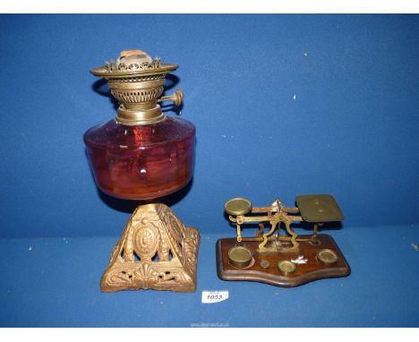 A 19th century Oil lamp on gilt metal base with cranberry glass reservoir plus a set of early 20th century Postal scales havi