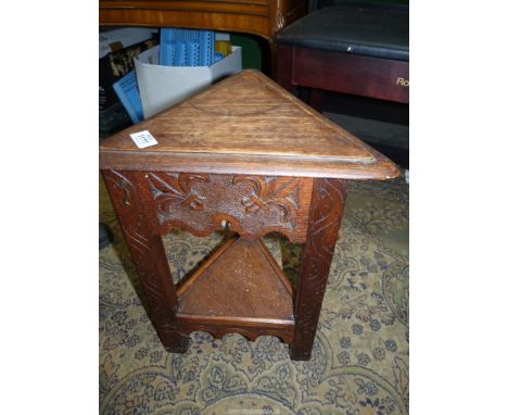 A carved Oak Sewing table/stool on three legs having lower shelf and lift top compartment, with some contents, spools, needle