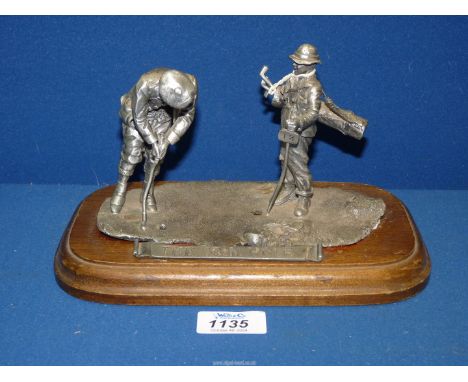 A cast Pewter model of a Golfer who is getting ready to putt while his caddy marks the hole, the figures are well modelled in