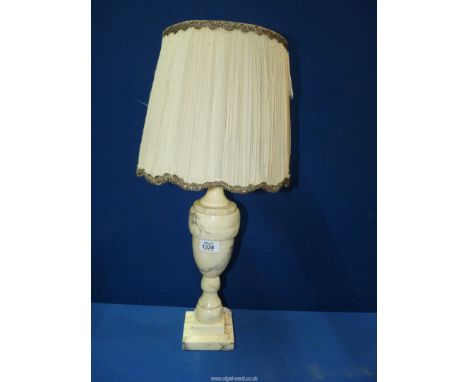 An Alabaster table lamp having silk shade with metallic threading to the top and bottom rim. 22 1/2" tall including shade.