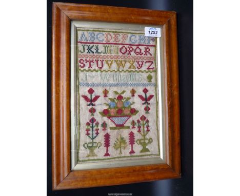 A small WElsh wool sampler by J. Williams, 19th c. with the alphabet and stylised motifs, 7'' x 11''.
