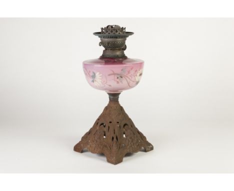 VICTORIAN PINK GLASS AND CAST METAL OIL TABLE LAMP, the floral painted reservoir above a square, spreading base cast with Art