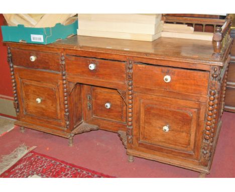 An Aesthetic Movement joined oak and elm kneehole writing desk, having three-quarter raised gallery with spindle brass turnin