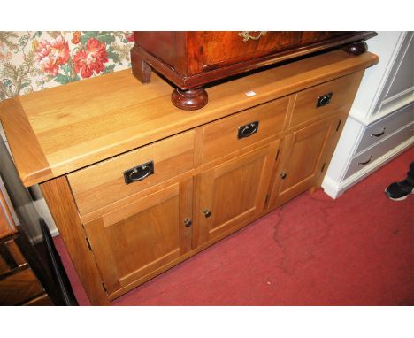 A contemporary light oak three door sideboard having three frieze drawers, width 148cm