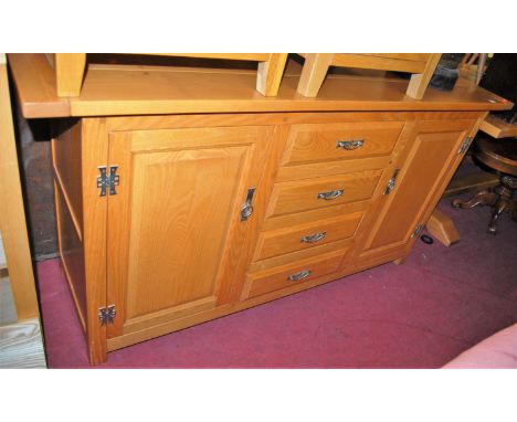A contemporary light elm planked top sideboard, having cleated ends, and four central drawers flanked by recessed panelled cu