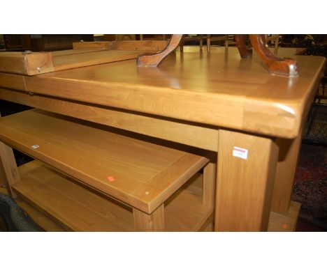 A contemporary light oak extending dining table, having pull-out action, two extra drop-in leaves, raised on square block sup