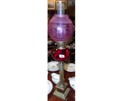 A Victorian Brass Oil Lamp with Corinthian Column and cranberry glass reservoir and etched pink glass shade.